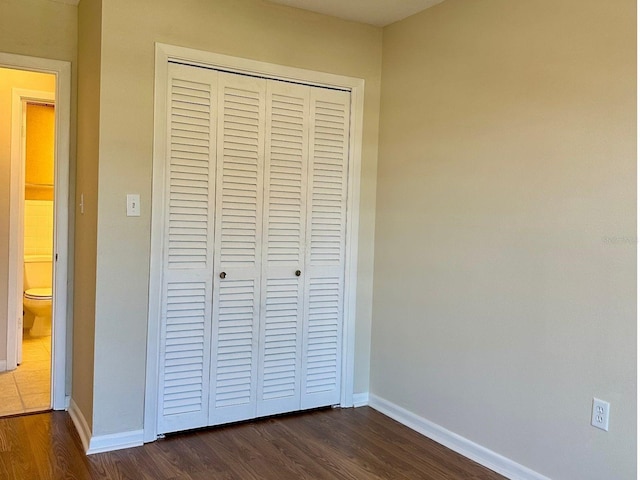 unfurnished bedroom with a closet and dark hardwood / wood-style floors