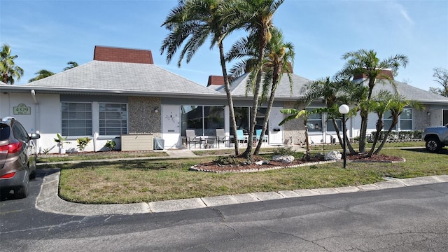 4329 Tahitian Gardens Cir Unit B, Holiday, FL 34691 - ranch-style house with a front yard, roof with shingles, and a patio