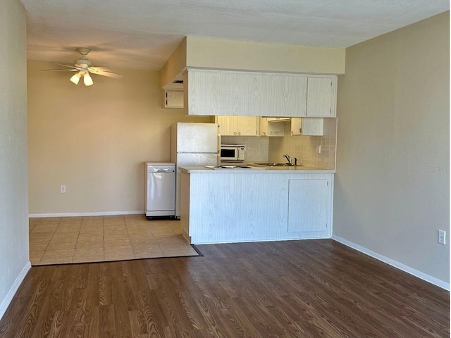 4329 Tahitian Gardens Cir Unit B, Holiday, FL 34691 - kitchen with white microwave, a ceiling fan, dark wood-style flooring, a peninsula, and backsplash
