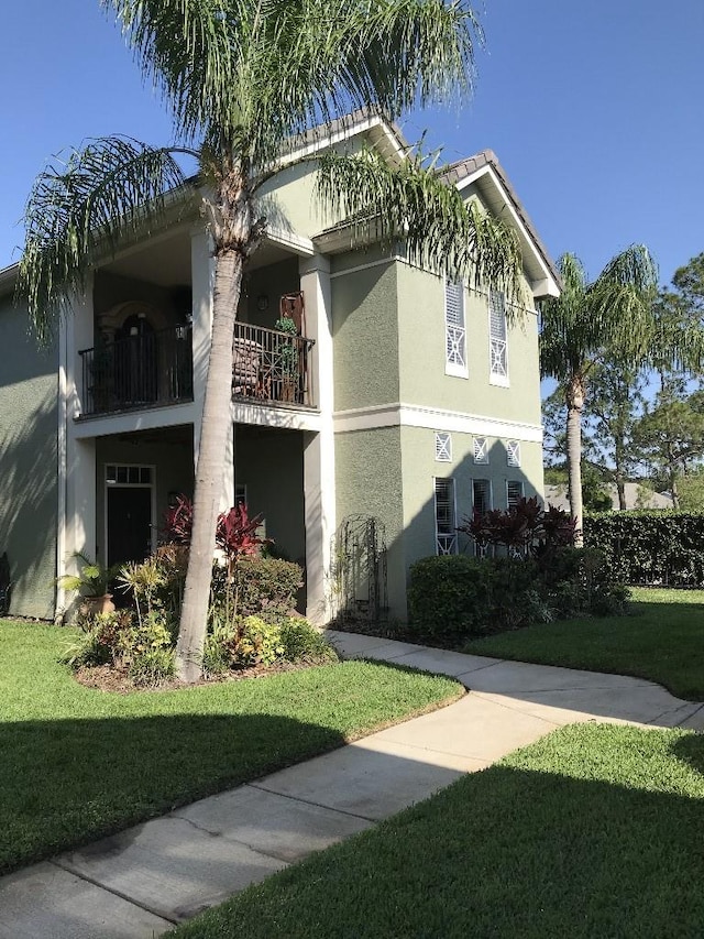 view of side of home with a balcony and a lawn