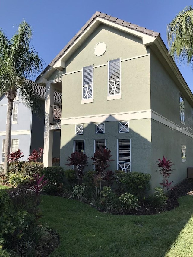 view of front of house featuring a balcony and a front yard