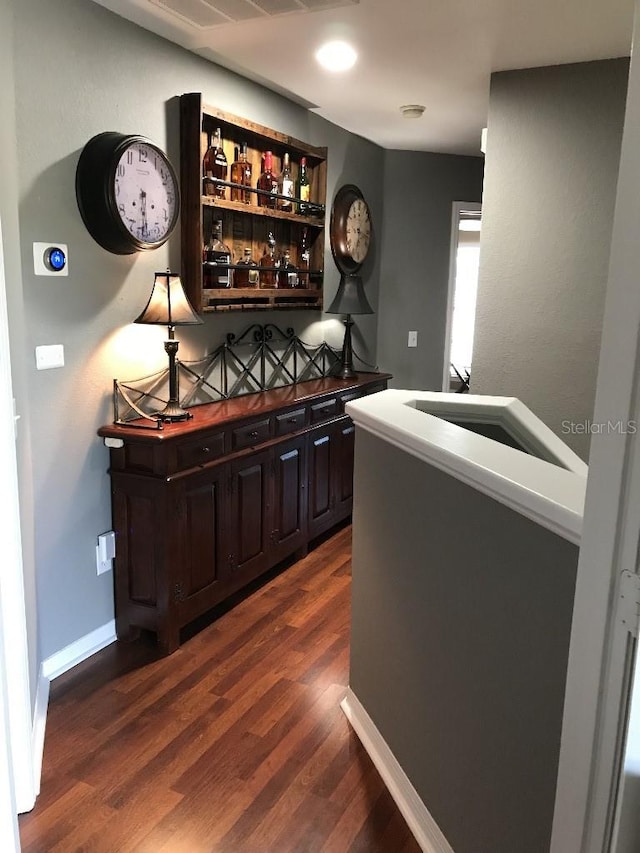 bar featuring dark brown cabinets and dark hardwood / wood-style floors