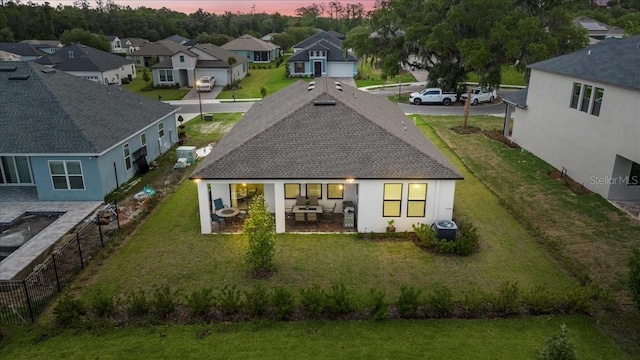 back house at dusk featuring a lawn, central AC, and a patio area