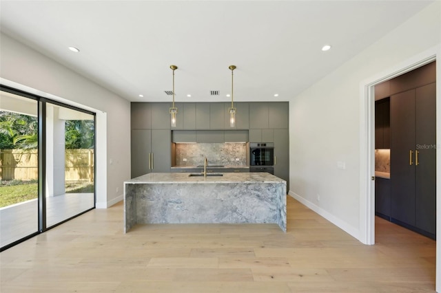 kitchen featuring pendant lighting, backsplash, gray cabinetry, and sink