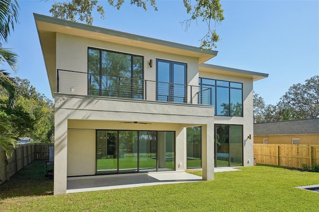 rear view of property with a patio, a balcony, ceiling fan, and a lawn