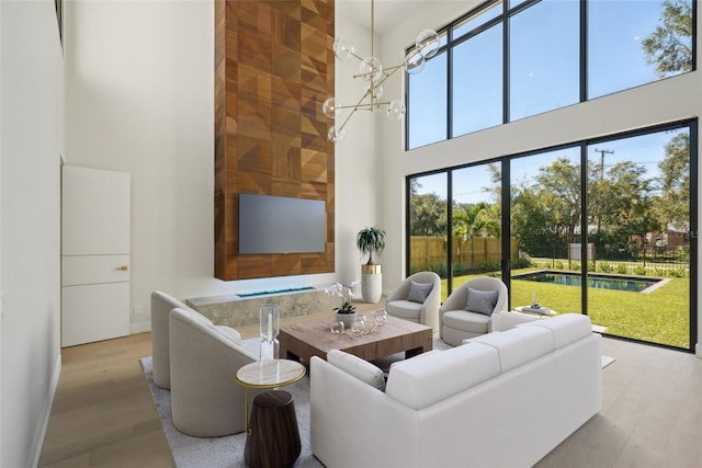 living room featuring light wood-type flooring, a towering ceiling, and a notable chandelier