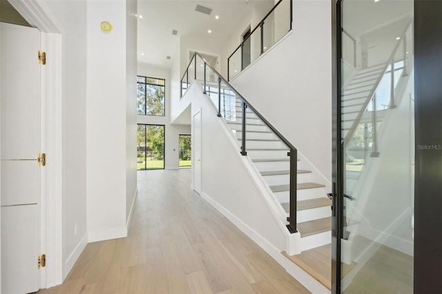 stairway featuring a towering ceiling and hardwood / wood-style flooring