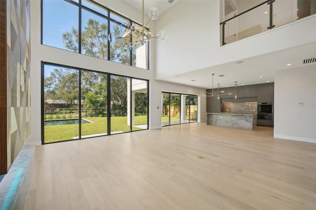 unfurnished living room featuring light wood-type flooring and a towering ceiling