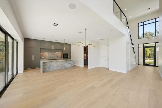 unfurnished living room with light hardwood / wood-style flooring, a notable chandelier, and sink