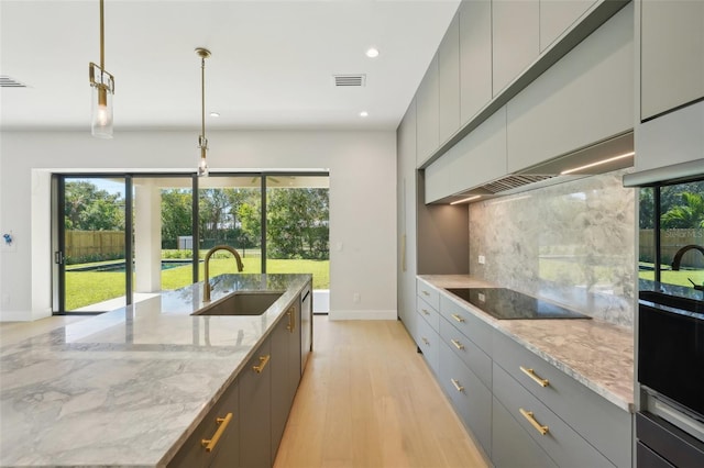 kitchen with sink, gray cabinets, light stone countertops, tasteful backsplash, and decorative light fixtures