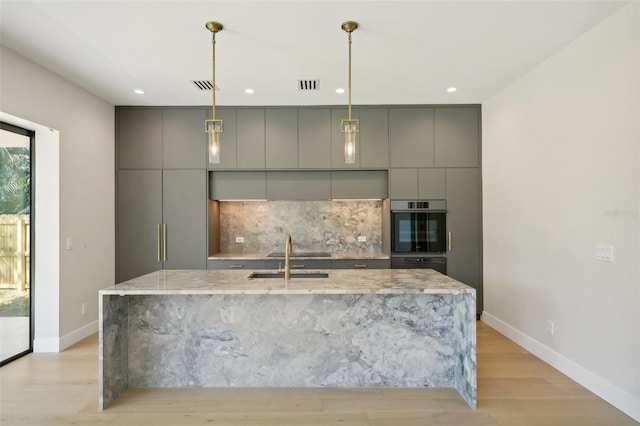 kitchen featuring pendant lighting, light stone counters, gray cabinetry, and stainless steel double oven