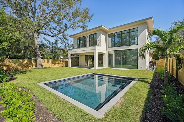 back of property featuring a yard, a balcony, and a fenced in pool