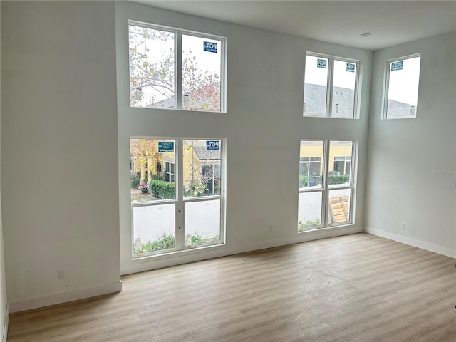 unfurnished living room featuring light hardwood / wood-style flooring and a high ceiling