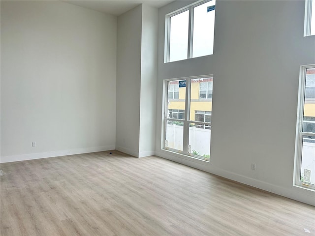 spare room with a healthy amount of sunlight, a high ceiling, and light wood-type flooring