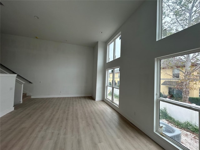 unfurnished living room with a high ceiling and light hardwood / wood-style floors