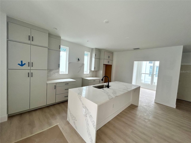 kitchen with a healthy amount of sunlight, a center island with sink, light hardwood / wood-style flooring, and sink