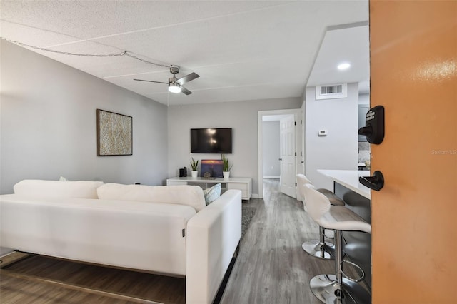 living room featuring hardwood / wood-style floors, ceiling fan, and a textured ceiling