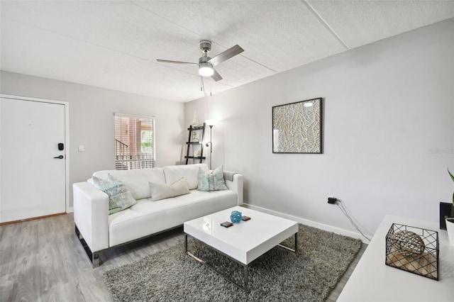 living room featuring hardwood / wood-style flooring, ceiling fan, and a textured ceiling