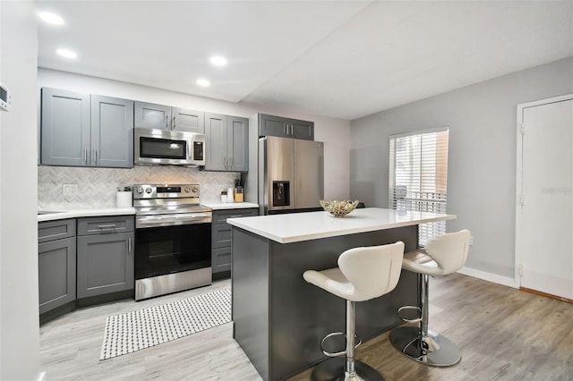 kitchen featuring light hardwood / wood-style flooring, tasteful backsplash, stainless steel appliances, and a center island