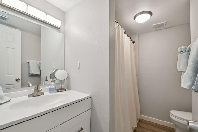 bathroom featuring wood-type flooring, toilet, and large vanity