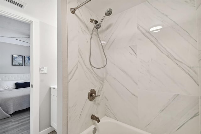 bathroom with tiled shower / bath combo, wood-type flooring, and vanity