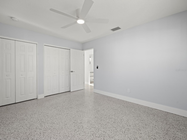 unfurnished bedroom with ceiling fan and two closets