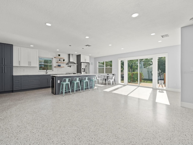 kitchen featuring gray cabinets, a kitchen bar, a kitchen island, tasteful backsplash, and stainless steel fridge