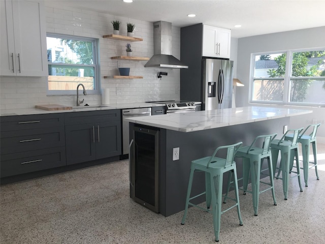 kitchen featuring white cabinets, tasteful backsplash, stainless steel appliances, and wall chimney exhaust hood