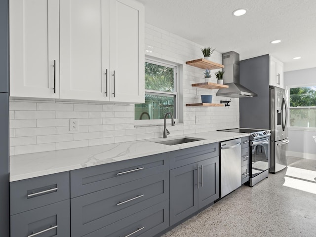 kitchen with white cabinetry, backsplash, appliances with stainless steel finishes, sink, and range hood