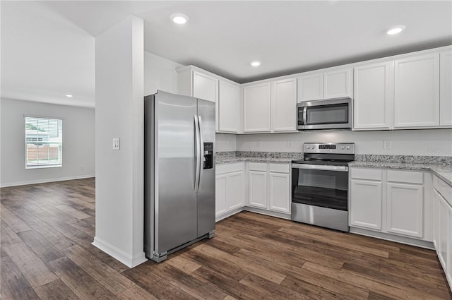 kitchen with white cabinets, dark hardwood / wood-style floors, light stone countertops, and appliances with stainless steel finishes