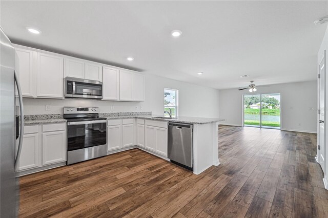 kitchen featuring ceiling fan, dark hardwood / wood-style flooring, kitchen peninsula, white cabinets, and appliances with stainless steel finishes