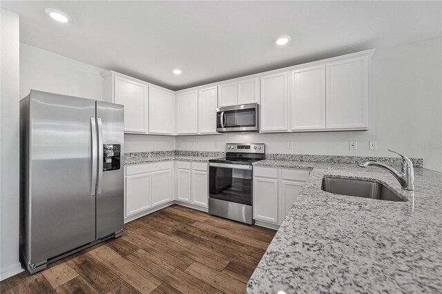 kitchen with light stone countertops, sink, white cabinetry, and stainless steel appliances