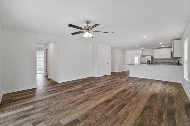 unfurnished living room featuring a wealth of natural light, dark hardwood / wood-style floors, and ceiling fan