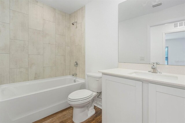 full bathroom featuring tiled shower / bath combo, toilet, wood-type flooring, and vanity