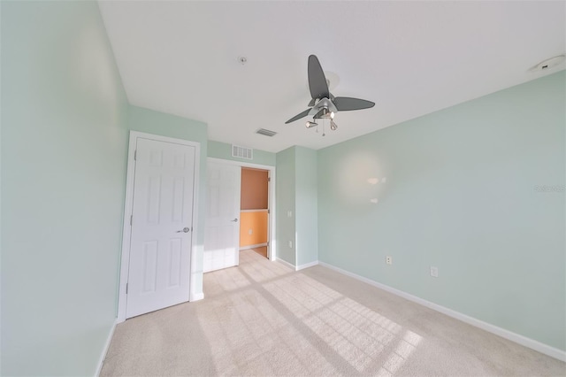 unfurnished bedroom featuring light colored carpet, a closet, and ceiling fan