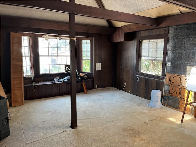 miscellaneous room with light carpet, wooden walls, and beamed ceiling