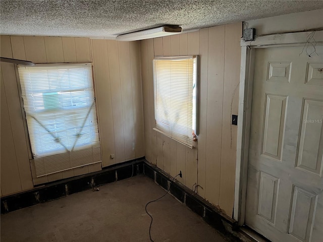 unfurnished room with carpet, wood walls, and a textured ceiling