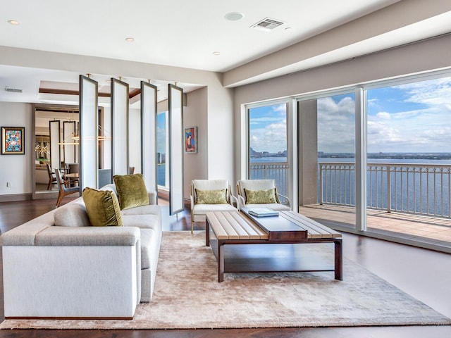 living area featuring a water view, baseboards, visible vents, and wood finished floors