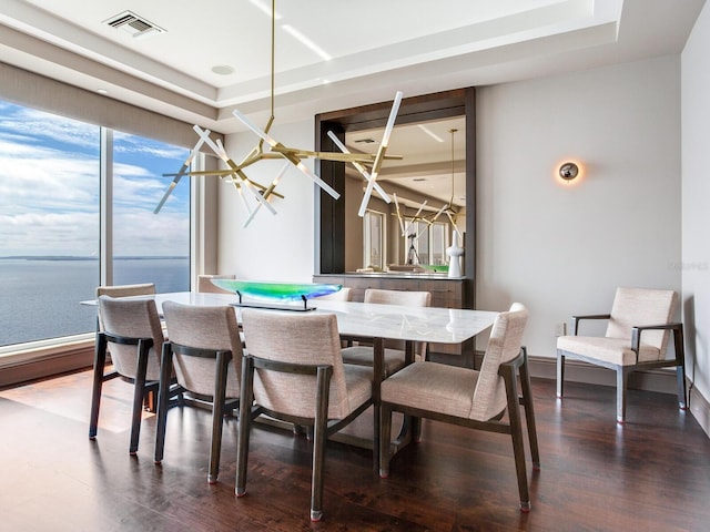 dining area featuring dark wood-type flooring, a raised ceiling, visible vents, and baseboards