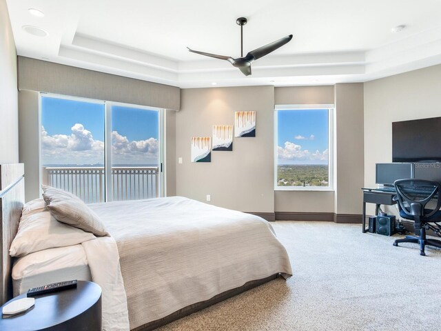 carpeted bedroom with baseboards, a tray ceiling, a ceiling fan, and access to exterior