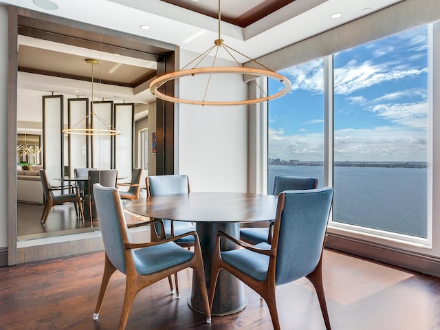 dining room with dark wood-type flooring, a tray ceiling, and an inviting chandelier