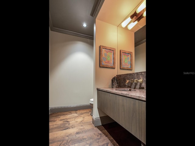 bathroom with tasteful backsplash, toilet, ornamental molding, wood finished floors, and vanity