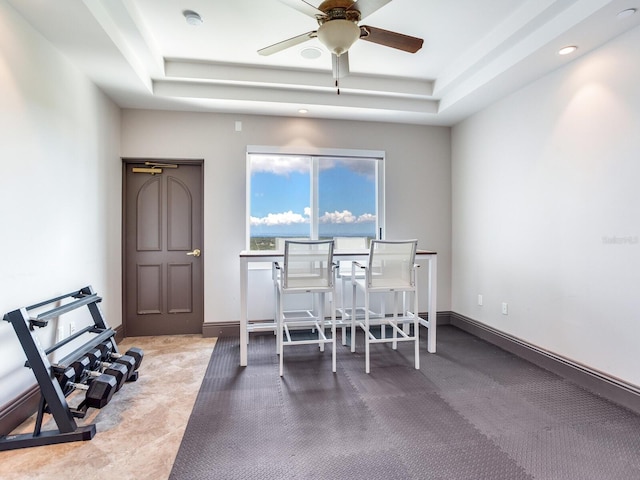 dining area featuring a raised ceiling, a ceiling fan, and baseboards