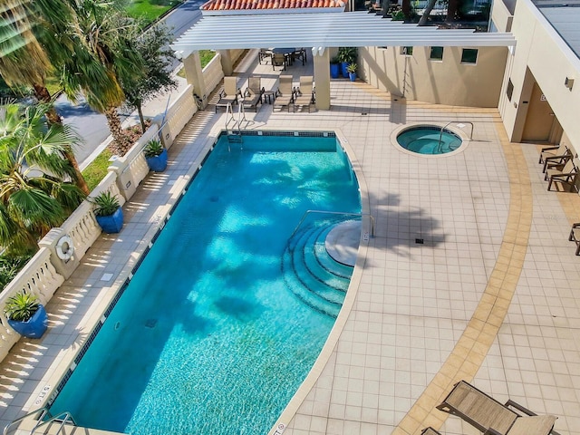 pool featuring a community hot tub, a patio area, and a fenced backyard