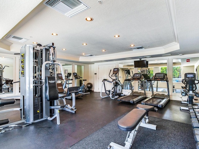 exercise room featuring visible vents, a textured ceiling, and ornamental molding