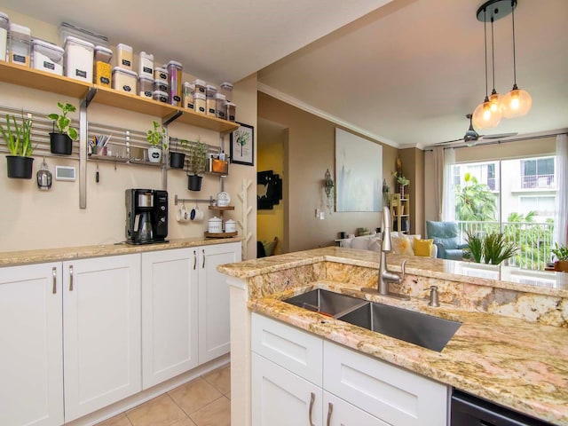 kitchen featuring sink, white cabinets, light stone counters, crown molding, and pendant lighting