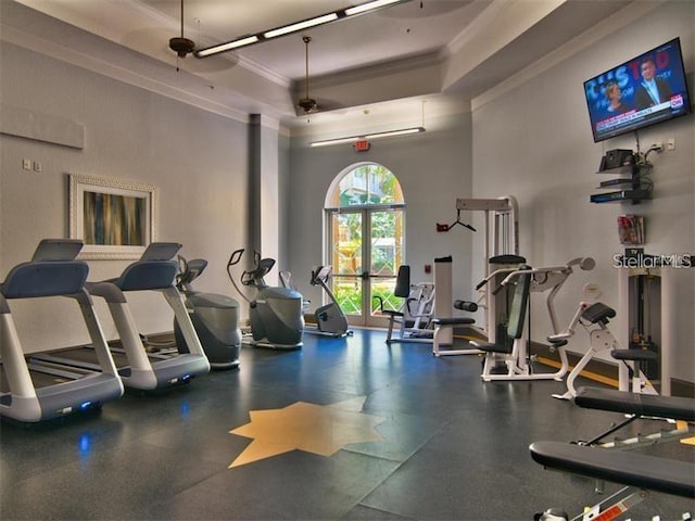 workout area featuring a tray ceiling, a towering ceiling, and ornamental molding