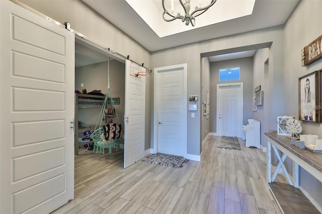 hallway with a notable chandelier, a barn door, and light hardwood / wood-style flooring