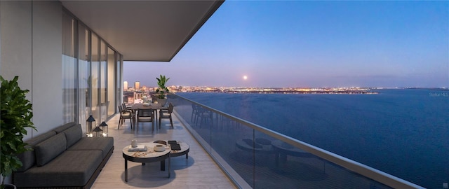 balcony at dusk featuring a water view