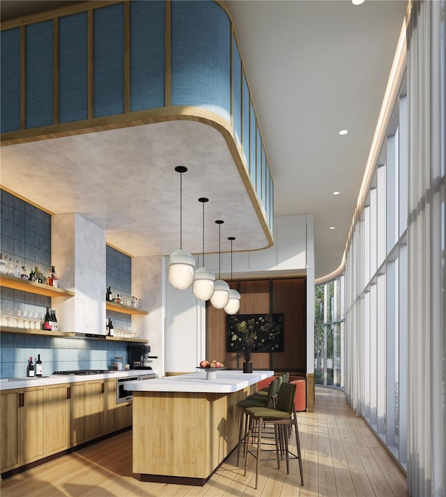 kitchen featuring a kitchen breakfast bar, decorative light fixtures, a kitchen island, backsplash, and light wood-type flooring